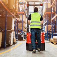 Man pushing forklift in warehouse