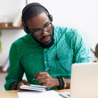 Man sitting at computer taking notes learning