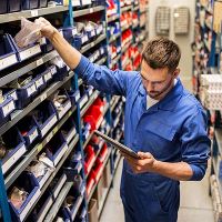 Man in car parts warehouse looking at tablet